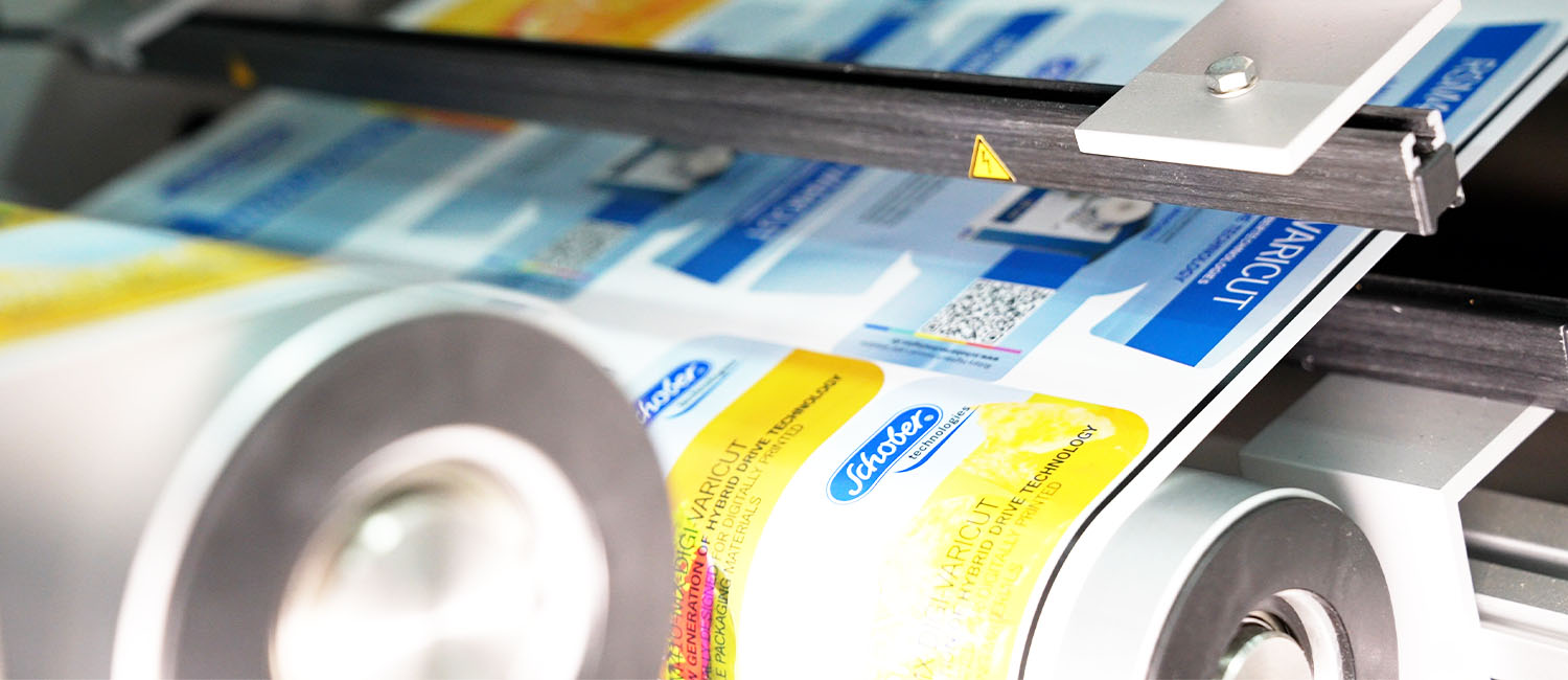 Eine bedruckte Papierbahn läuft über Rollen und unter einer Antistatik-Einrichtung durch.
